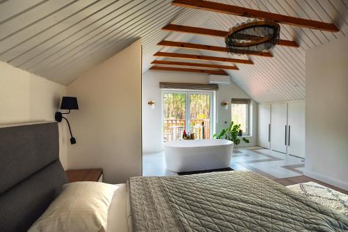 a bedroom with a bed and a bath tub at Заміський будинок з каміном та ванною з панорамним видом в ліс in Novosilki