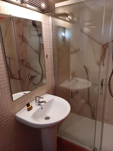 a bathroom with a sink and a shower and a mirror at Oficina Do Joe Guesthouse in Outeiro