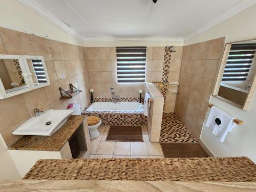 a bathroom with a tub and a toilet and a sink at Mazi Vuwu Ponta Malongane in Ponta do Ouro