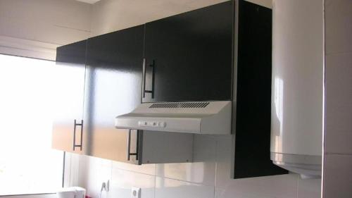 La cuisine est équipée de placards noirs et d'un four avec plaques de cuisson blanches. dans l'établissement BOUZNIKA T10, à Bouznika