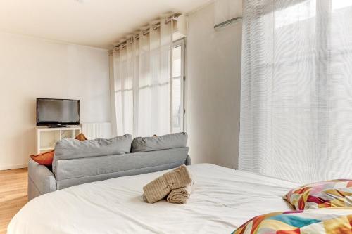 ein Wohnzimmer mit einem Bett und einem Sofa in der Unterkunft Le Curie - Saint Cyr in Saint-Cyr-lʼÉcole