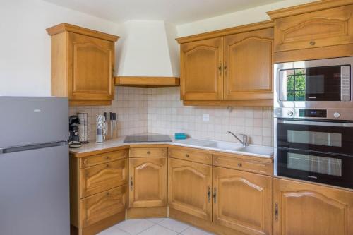- une cuisine avec des placards en bois et un réfrigérateur blanc dans l'établissement Paisible maison proche Chambord, à Beaugency
