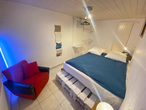 a bedroom with a bed and a red chair at Apart'Hotel du Faubourg by Stay Swiss in Porrentruy