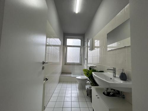 een witte badkamer met een toilet en een wastafel bij SKY Apartments Hannover in Hannover