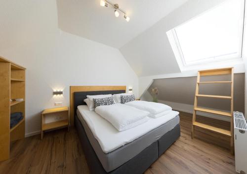 een slaapkamer met een groot bed met witte lakens en een raam bij Pension Sonne Appartements in Minden