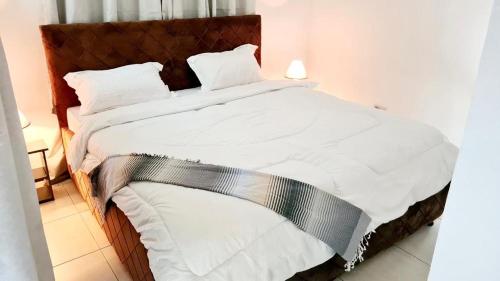 1 cama grande con sábanas y almohadas blancas en Luxurious apartment with King size bed, en Dar es Salaam
