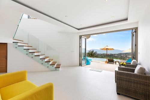 a living room with a staircase and a yellow chair at Villa Pearl - Amazing View in Amphoe Koh Samui