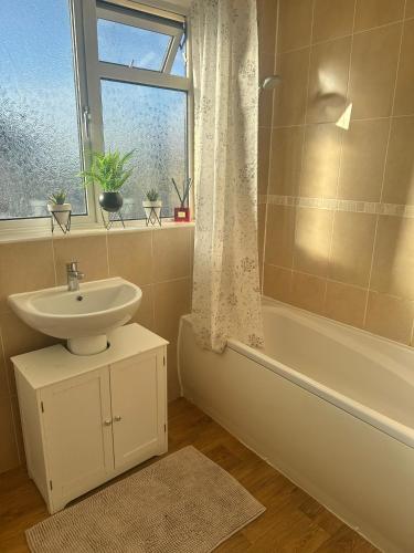 een badkamer met een wastafel, een bad en een raam bij 3-Bedroom house with private driveway in Adel