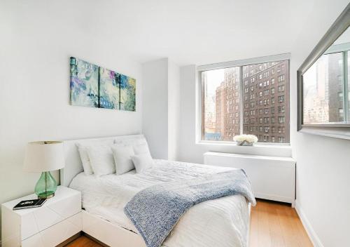 um quarto branco com uma cama e 2 janelas em Stylish 2 BD 2 BA At UES em Nova York