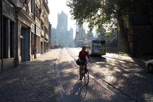 a person riding a bike down a street with a bus at Hotel Gravensteen in Ghent