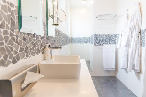 a white bathroom with a sink and a mirror at Hôtel La Baie des Anges, son SPA marin & sa piscine couverte et chauffée in Landéda