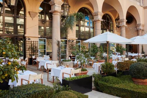 a restaurant with tables and umbrellas in front of a building at The Maybourne Beverly Hills in Los Angeles