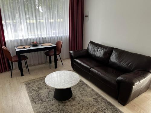 a living room with a leather couch and a table at Luxuria Modern Apartments - Self Check-in in Šiauliai