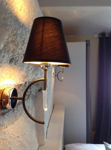 a lamp attached to a wall next to a bed at Hôtel Restaurant de la Place in Saint-Jean-dʼAngély