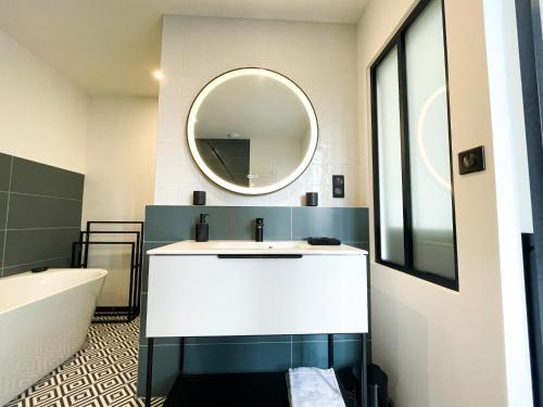 une salle de bain avec un lavabo blanc et un miroir dans l'établissement Le Petit Rousseau - Maison Climatisé By Primo, à Hurigny