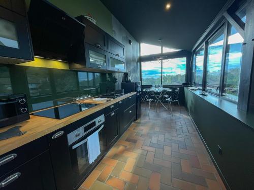 une cuisine avec des armoires noires et une grande fenêtre dans l'établissement Le Petit Rousseau - Maison Climatisé By Primo, à Hurigny