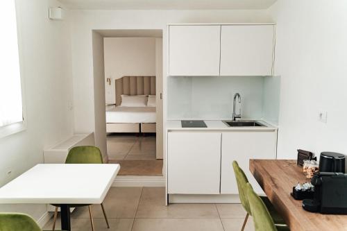 eine Küche mit weißen Schränken sowie einem Tisch und Stühlen in der Unterkunft Le Vie Del Centro Luxury Room in Matera