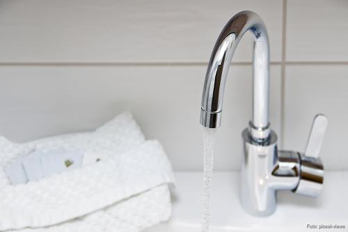 a faucet with water coming out of it next to towels at Gasthof & Landhotel Ohrnbachtal in Weilbach