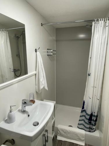 a white bathroom with a sink and a shower at The Ocean Guesthouse in Weymouth