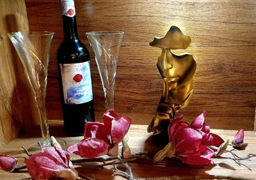 eine Flasche Wein neben zwei Weingläsern und Blumen in der Unterkunft Appartementwohnung Central Bad Sachsa in Bad Sachsa