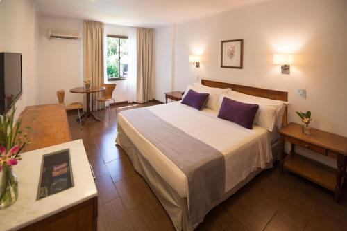 a hotel room with a large bed with purple pillows at Hotel Saint George in Puerto Iguazú