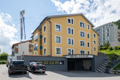 a yellow building with cars parked in a parking lot at Boutique Hotel Cervus in St. Moritz