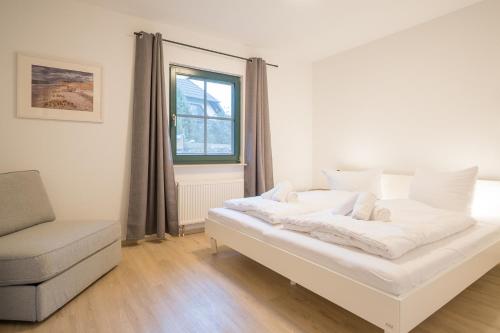 uma cama num quarto com uma cadeira e uma janela em Ferienwohnung Lee West 2 2 em Dierhagen