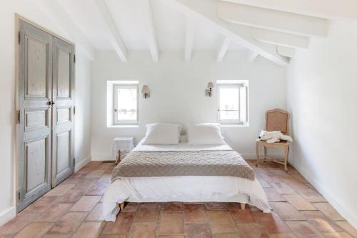 sypialnia z dużym łóżkiem w białym pokoju w obiekcie La Demeure Provençale au charme suranné w mieście Nîmes