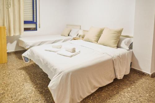 um quarto com 2 camas e lençóis brancos em COSTA AZUL em Puerto de Sagunto