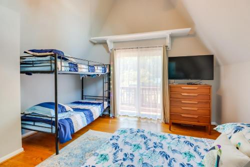 a bedroom with two bunk beds and a television at Beachy Maryland A-Frame Steps to Chesapeake Bay! in Ridge