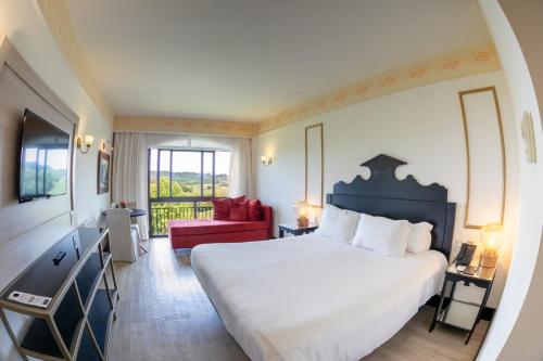 um quarto com uma grande cama branca e uma cadeira vermelha em Spa do Vinho Condomínio Vitivinícola em Bento Gonçalves