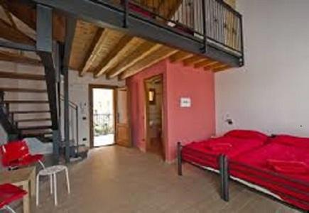 Cette grande chambre comprend un lit rouge et un escalier. dans l'établissement Cascina Amrit CAV, à Borghetto Lodigiano