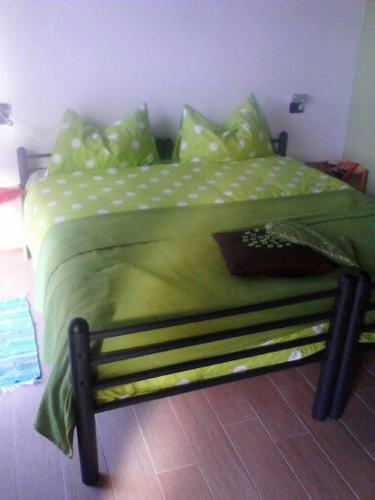a bed with a green comforter and pillows at Cascina Amrit CAV in Borghetto Lodigiano