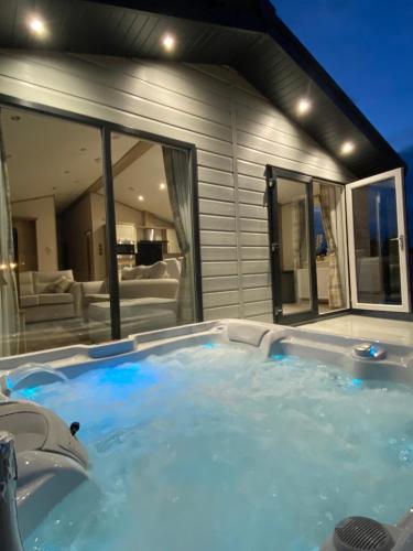 un grand bain à remous en face d'une maison dans l'établissement The Retreat Hot Tub Lodge - Golden Palm Resort (21), à Skegness