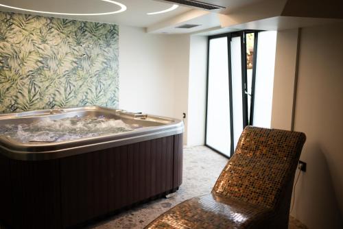 a bath tub in a room with a chair at HOTEL GRACIAN in Sremska Mitrovica