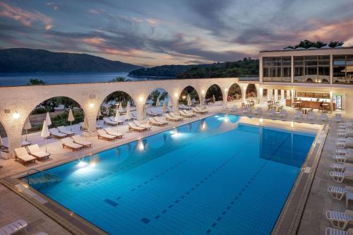 uma grande piscina com espreguiçadeiras e um edifício em Arkada Hotel em Stari Grad