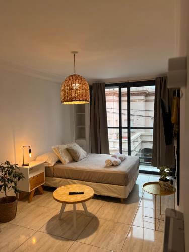 Un dormitorio con una cama, una mesa y una lámpara de araña. en Céntrico mono ambiente completo y amplio, en Santa Fe