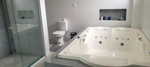 a white bathroom with a tub and a toilet at Pousada Rota do Sol Bombinhas suítes com café e sem limpeza diaria in Bombinhas