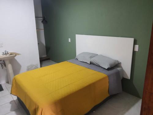 a bedroom with a bed with a yellow and gray blanket at Casa Tanah in Guadalajara