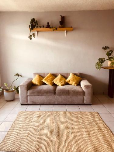 a couch with yellow pillows in a living room at Casa Tanah in Guadalajara