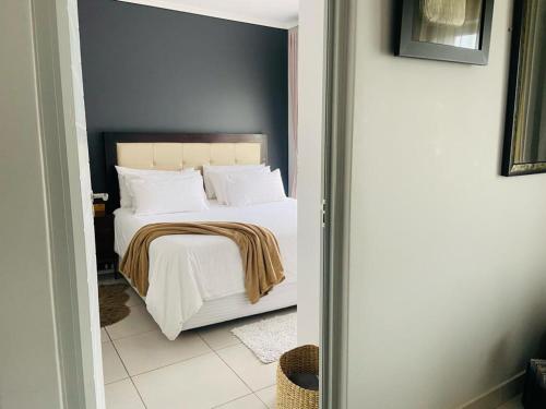 um quarto com uma cama com lençóis brancos e almofadas em Green Valley Bliss em Boschrand