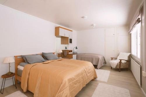 a white bedroom with a bed and a chair at Spacious house near santapark in Rovaniemi