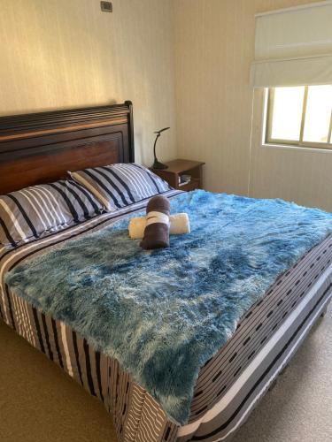 um urso de peluche sentado numa cama com um cobertor azul em Casa condominio para 3 personas em Angol
