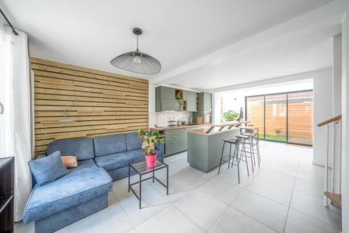 ein Wohnzimmer mit einer blauen Couch und einer Küche in der Unterkunft Maison rénové proche Paris 15. in Malakoff