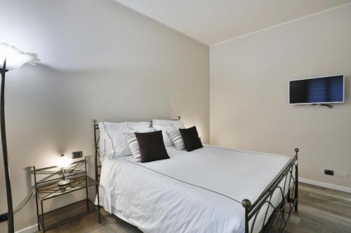 a bedroom with a bed with white sheets and a tv at DANTE SUITE in Como