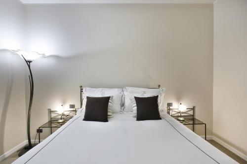 a white bed with two black pillows at DANTE SUITE in Como