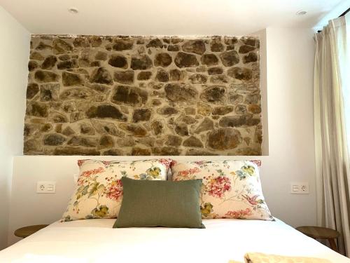 een slaapkamer met een stenen muur achter een bed bij GURAH Boutique Apartments in Bakio