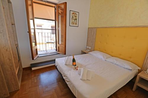 een slaapkamer met een wit bed, handdoeken en een raam bij Romerooms Condotti in Rome
