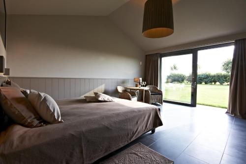 a bedroom with a bed and a large window at Tannine et Cuisine in Jabbeke