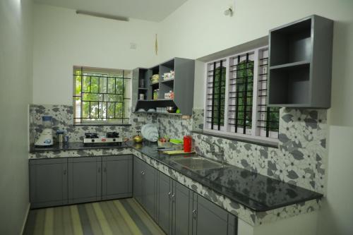 a kitchen with gray cabinets and a black counter top at LA CASA THE HOMESTAY in Trivandrum